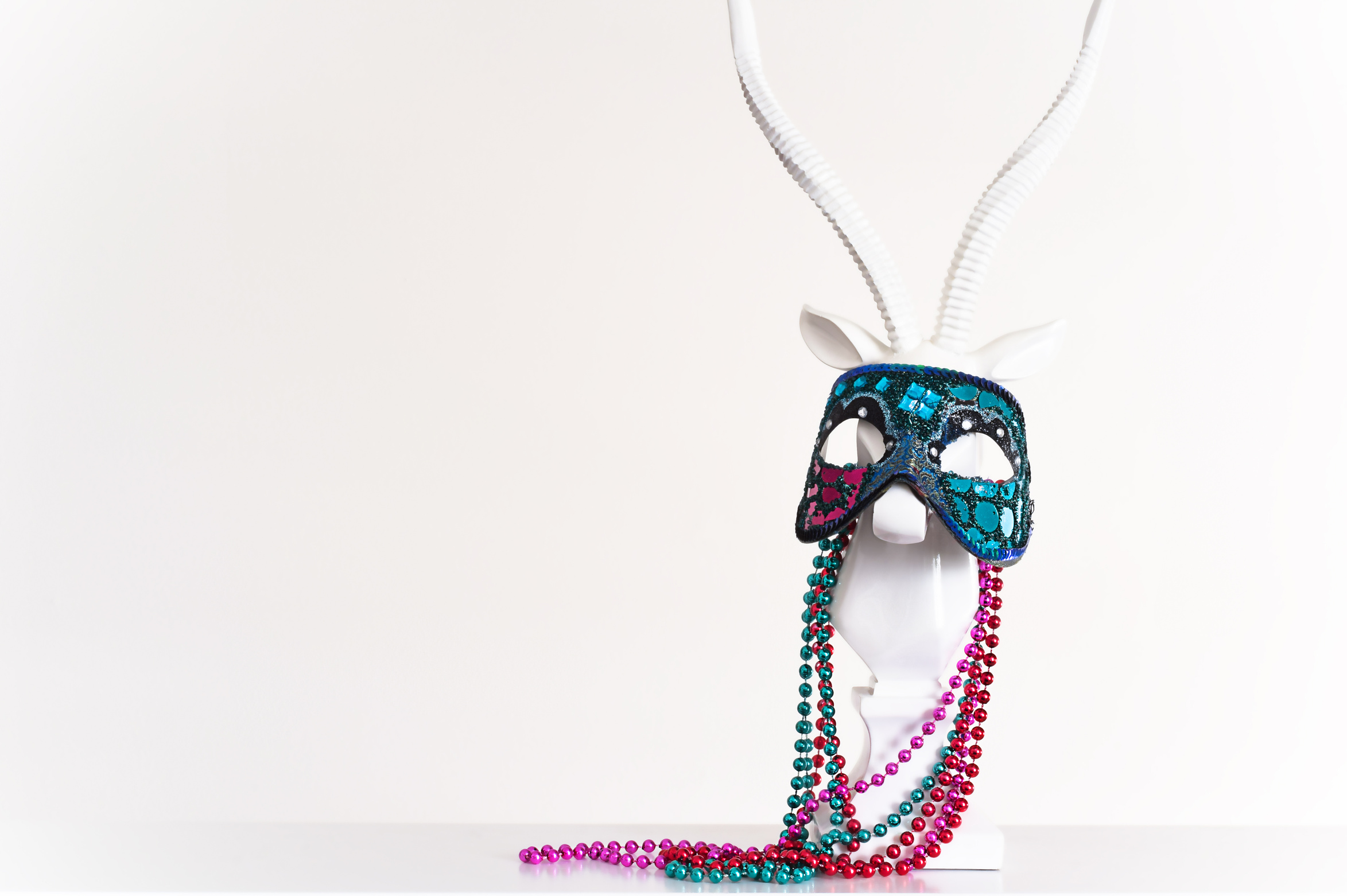 Mardi Gras Mask and Beads on White Animal Statuette with Horns